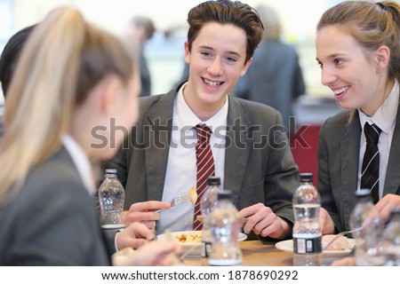 Portrait shot of middle school students eating lunch in the school cafeteria.