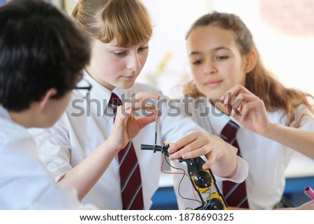 A group of high school students assembling a robot during a science class.