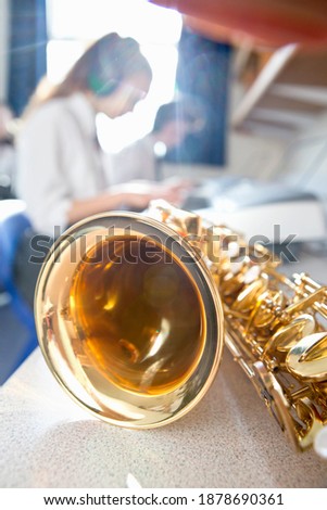 Vertical shot of a shiny brass saxophone on table in a high school music class