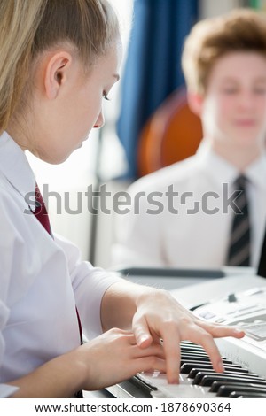 Close-up shot of a high school student playing piano during a music class.