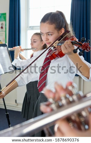 Vertical shot of a high school student playing violin during a music class.
