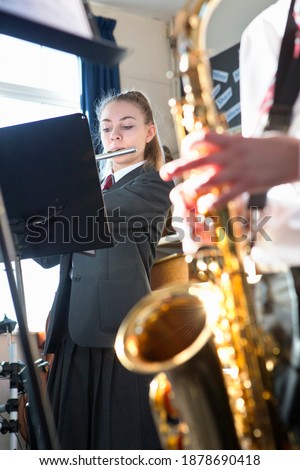 Vertical shot of a high school students playing a saxophone flute in a music class.