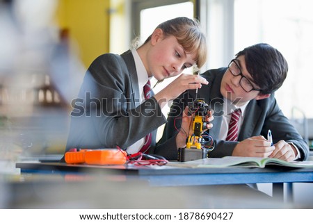 High school students assembling a robot during a science class.