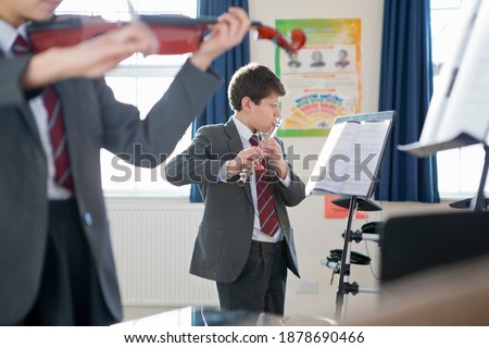 High school students playing a flute and violin during a music class.
