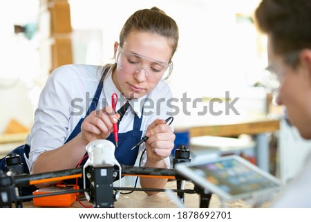 Portrait shot of a high school girl testing the electronics of a drone in a shop class.