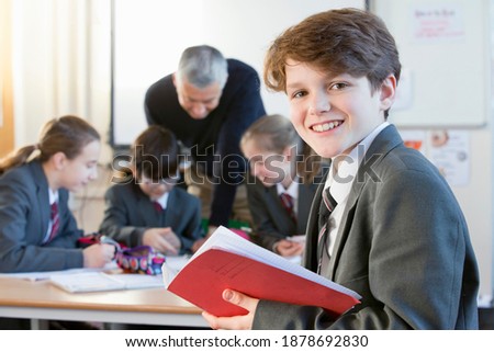 Portrait of a middle school student holding a notebook and smiling at the camera.