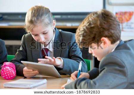 Middle school girl doing her homework on a digital tablet in the study hall.