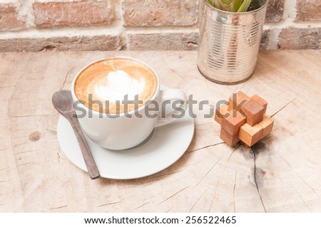 A cup of coffee with wood puzzle on wooden table