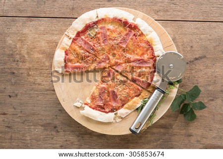 Pizza on wooden table with pizza cutter