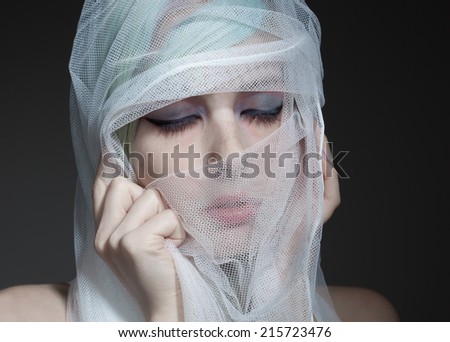 Closeup portrait of a young woman covering her face with a veil.