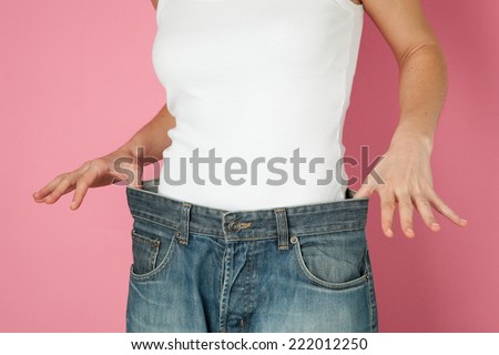 woman who has lost weight holding a loose trousers.