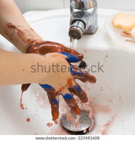 Child washing dirty hands of paint.