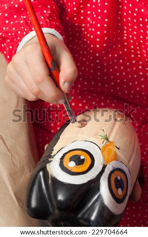Child painting an owl made of recycled plastic bottle.