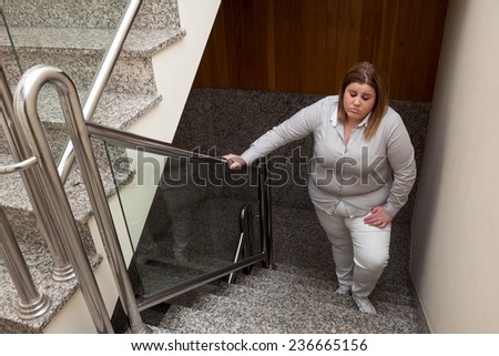 Fatigued woman going upstairs.