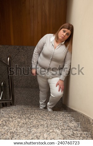 Fatigued woman is leaned against a wall.