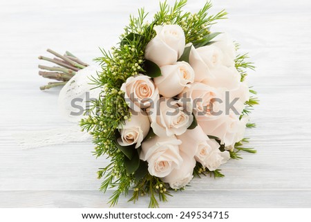White Roses wedding bouquet on a white wood surface.