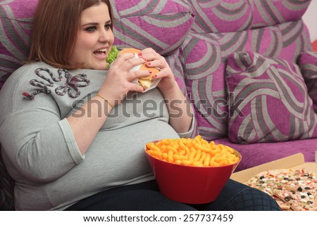 Sedentary woman eating fast food on the couch