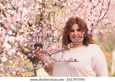 Plus size woman posing beside plum tree
