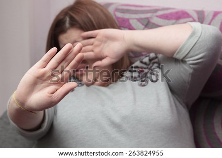 Woman saying stop with her hands and covering face. Selective focus on her hand.