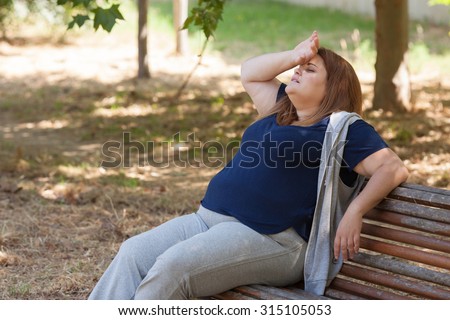 Fatigued overweight woman sitting on a bench