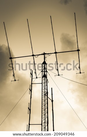 Antennas high against the sky brown.