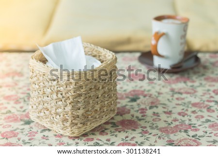 wicker tissue box on the table cloth flowers, warm tone photo.