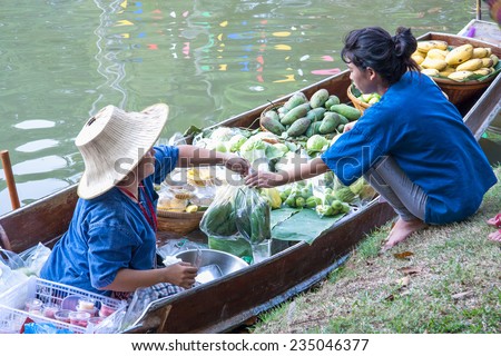 BANGKOK , THAILAND - NOVEMBER 30 : Unidentilied women buy a mango in floating market on November 30 , 2014 in Suan Luang Rama XI park , Bangkok , Thailand.