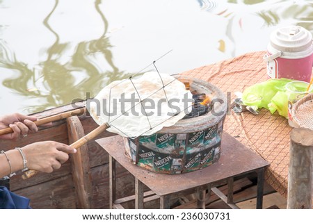 BANGKOK , THAILAND - NOVEMBER 30 : Unidentilied man  try to grill a crisp rice in a boat shop on November 30 , 2014 in Suan Luang Rama XI park , Bangkok ,Thailand. Crisp rice is a snack in Thai food.