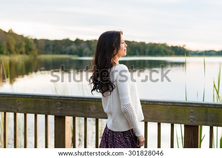 Smiling, pretty brunette on Fall nature walk with tall grass and lake in background
