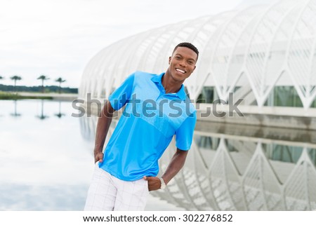 Black, African American college student wearing blue polo shirt, shorts with hands in pockets