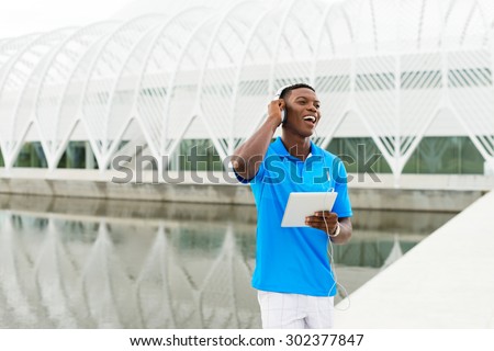 Black, African American college student wearing headphones and listening to music on a digital tablet computer