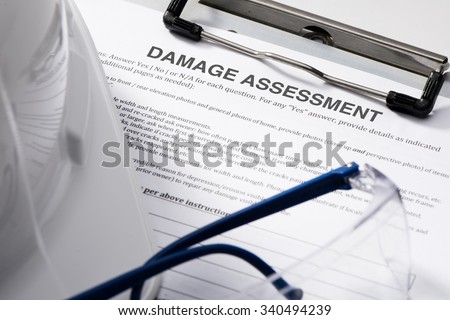 Damage assessment form with safety glasses and hardhat on clipboard