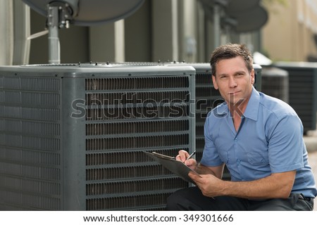 Thirtyish air conditioning repairman with clipboard