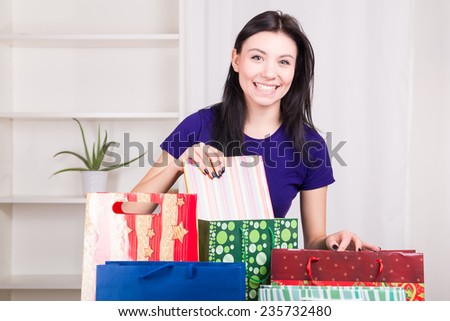 Smiling happy girl prepares bags gifts for Christmas