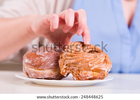 Hand reaches for the sweet donuts on the table in the kitchen