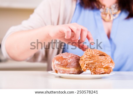 Hand reaches for the sweet donuts on the table in the kitchen