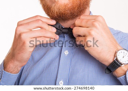 Bearded man ties a bow tie at the collar - studio shoot