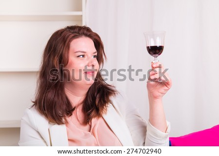 Plump and young woman tests a glass of red wine - studio shoot
