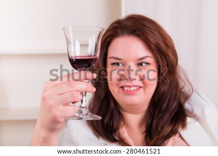 Plump and cheerful woman holding a glass of red wine