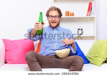 Happy man with bear and popcorn on the sofa