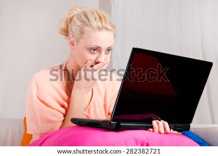 Shocked girl watching laptop at home