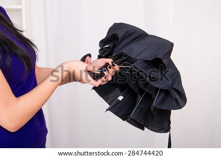 Woman opening black umbrella at home