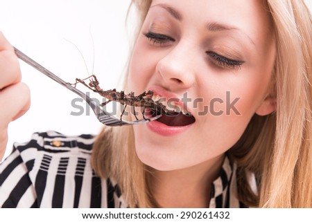 Woman eating big insects with a fork in a restaurant