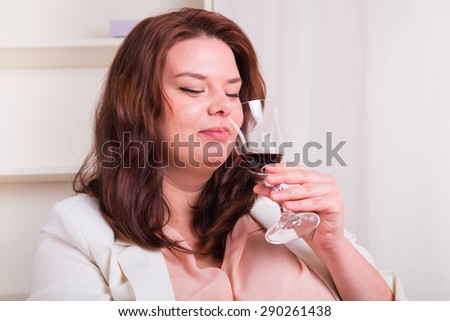 Plump and elegant woman tests a glass of red wine