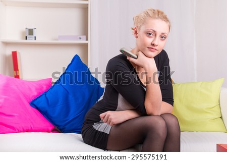 Elegant woman watching television at home on the sofa