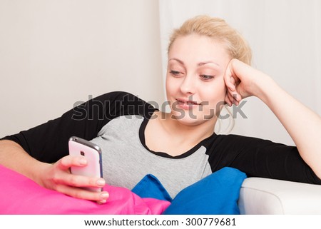 Girl lying on the sofa with a smartphone and texting at home