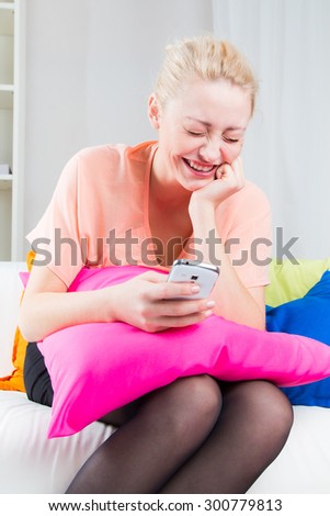 The girl laughs and read sms on smartphone at home