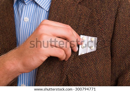 Man pulls medicine from his pocket in the jacket - studio shot