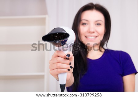 Hair dryer and young smiled girl at home