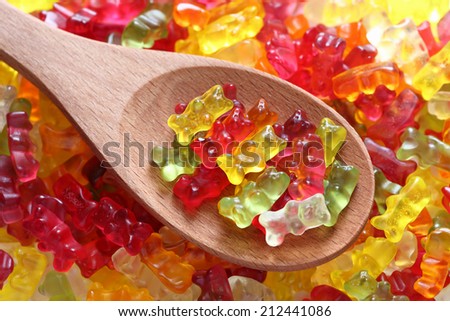 Gummy bears on a wooden spoon on a gummy bear background. Close-up.